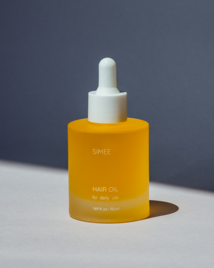Minimalistic shot of Simee Hair Oil with dropper on solid grey background and shadow